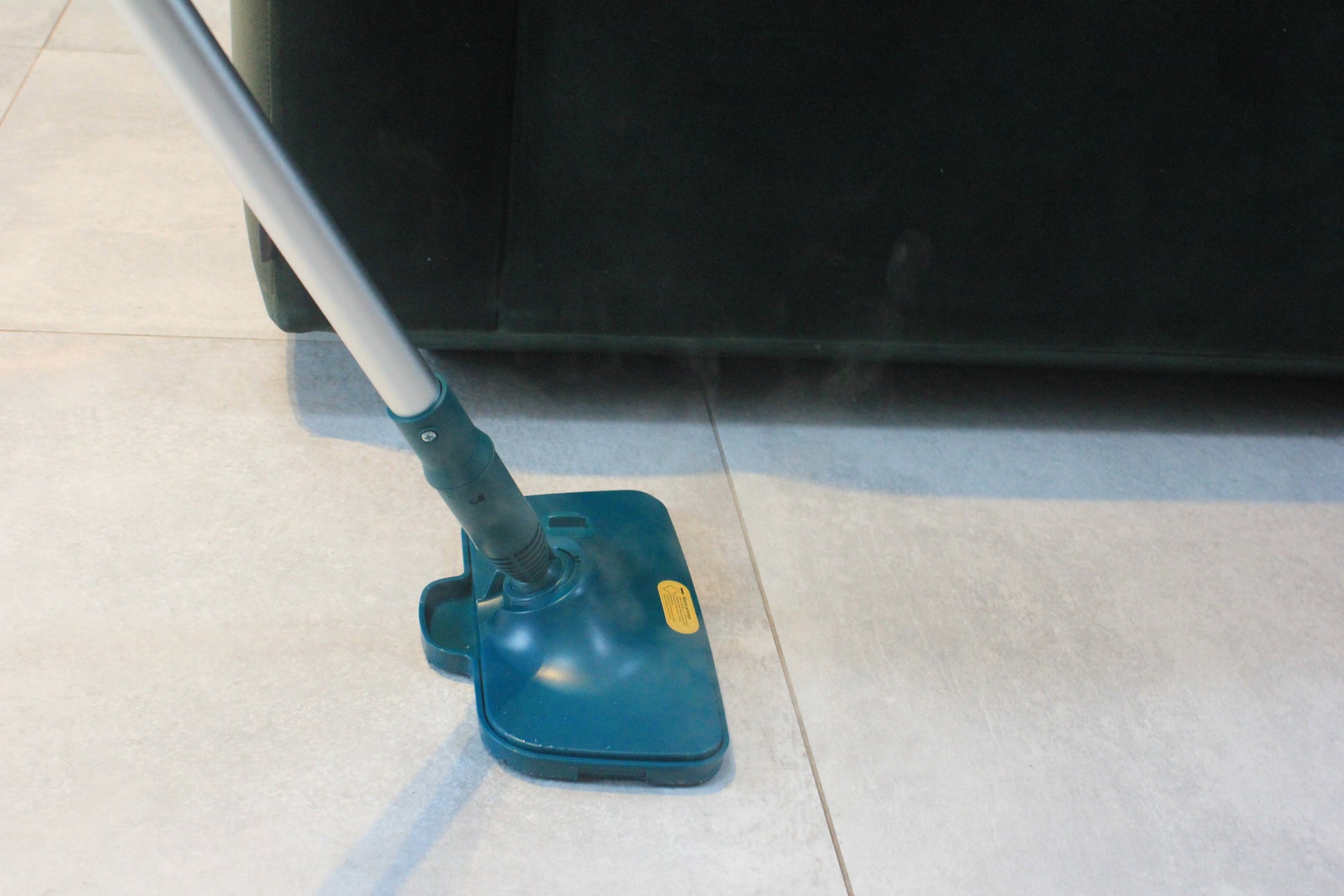 ScandiSteam dampmoppe rengør effektivt gulvet med damp på lyse fliser ved en sofa